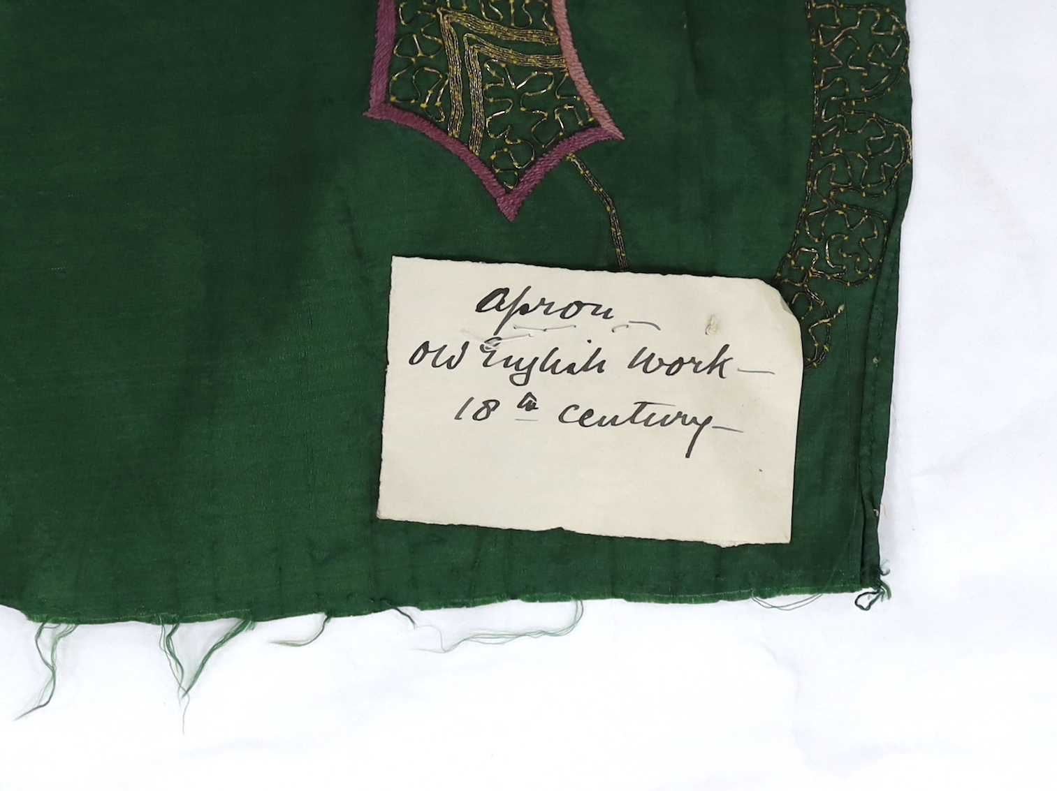 A late 18th century green silk scalloped bordered lady’s apron border, ornately embroidered with gold metallic threads and polychrome silk, in a large vine, floral and leaf design, together with a similar cream silk embr